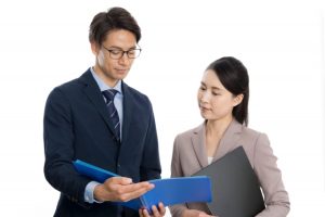男女の探偵が調査資料を見ている様子