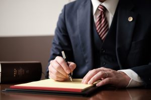 リーガルパッドにメモをする男性弁護士の手元